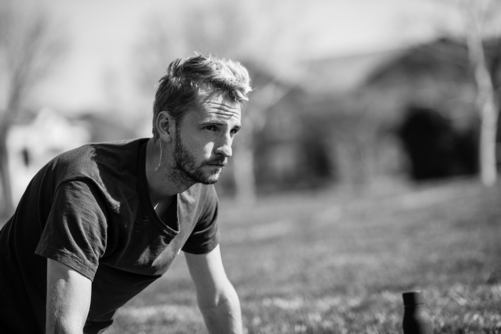 black and white image of pro soccer player Villyan Bijev sitting in the grass and staring off into the distance
