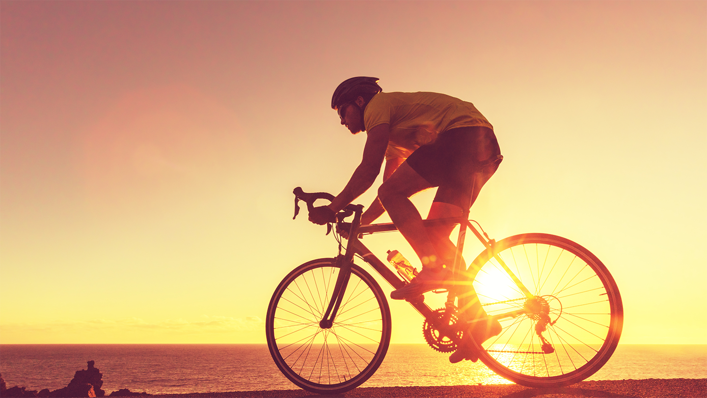 A man is riding a bike at sunset showcasing the role of gut health and athletic performance