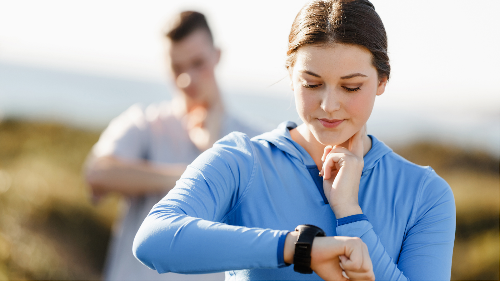 A photo of a woman checking her pulse and monitoring her heart rate on a smart watch. 