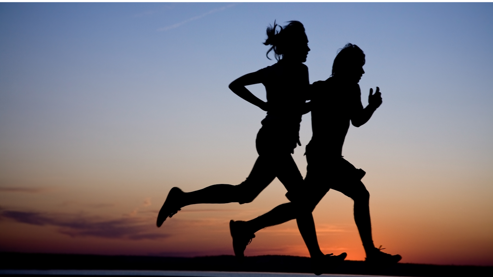 The silhouette of two people running with a sunset in the background, working on improving their VO2 Max. 